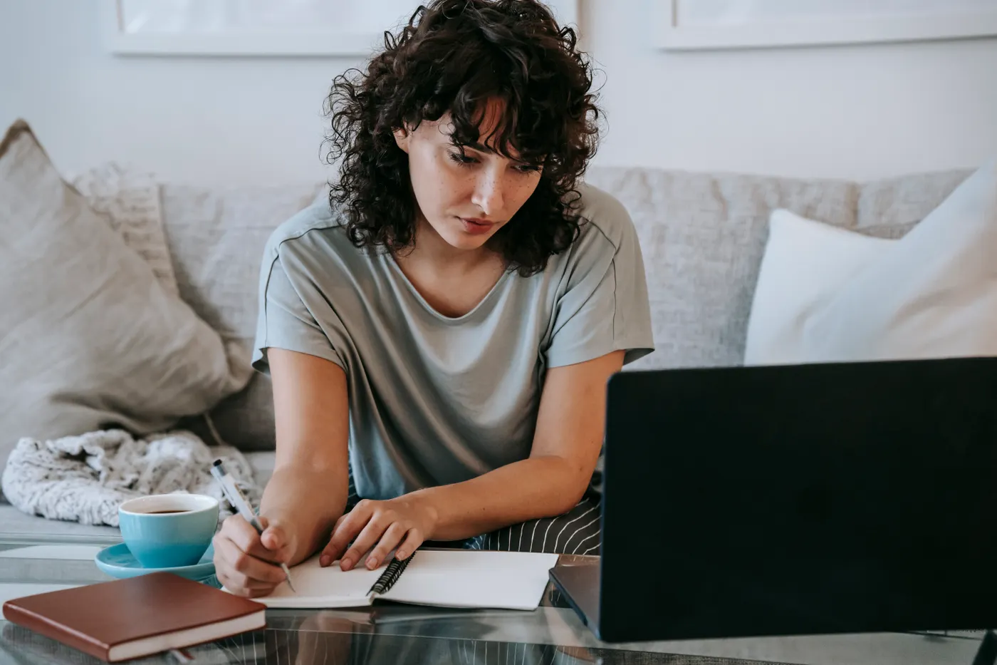 Adult student taking notes while completing online high school coursework on a laptop